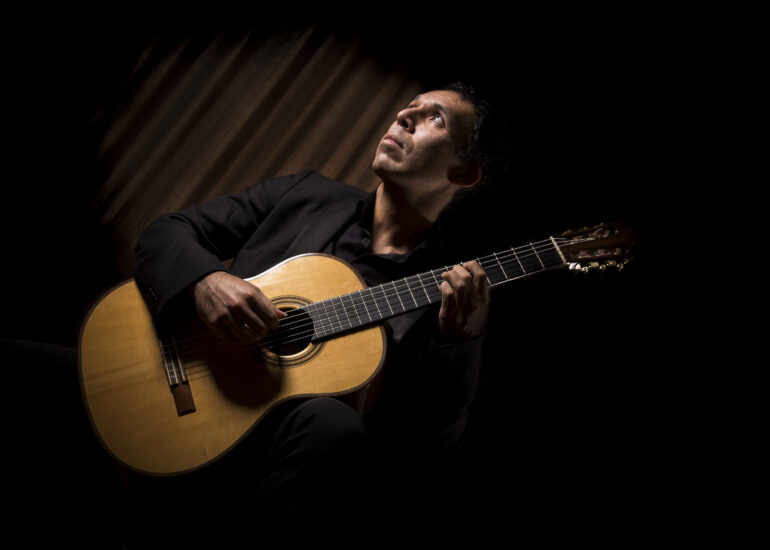 Foto do designer Denis Moribe sorrindo segurando uma caneta