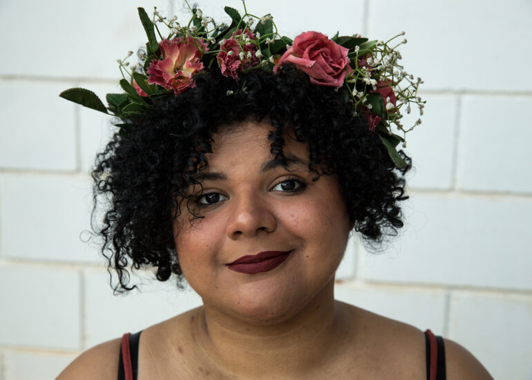 Foto do designer Denis Moribe sorrindo segurando uma caneta