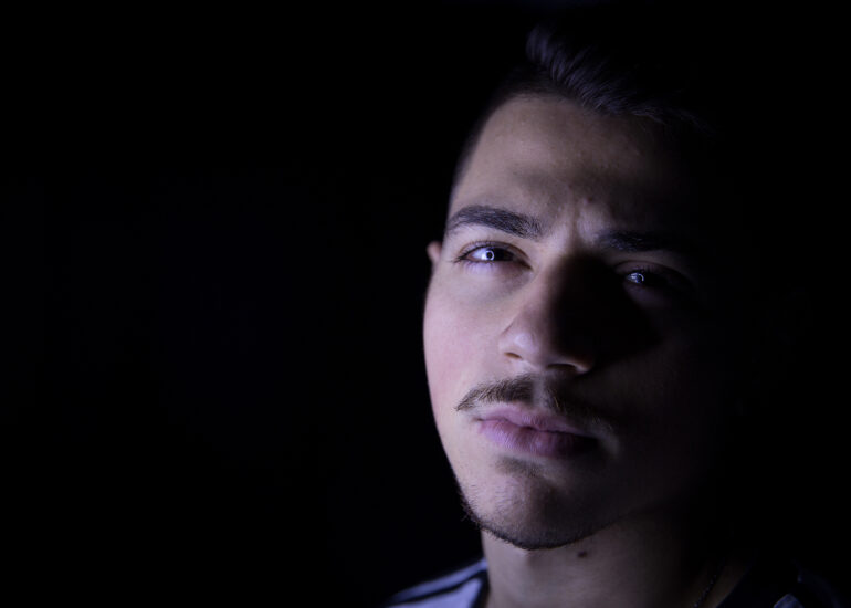 Foto do designer Denis Moribe sorrindo segurando uma caneta