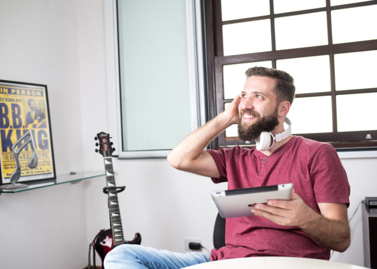 Foto do designer Denis Moribe sorrindo segurando uma caneta