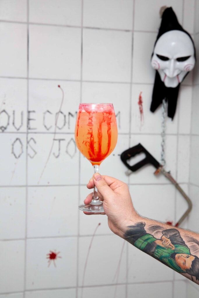 Drink laranja e vermelho com o tema jogos mortais feito para o Fantasmagória bar