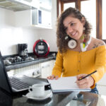 Imagem de uma mulher ouvindo música e tomando café em uma cozinha de manhã